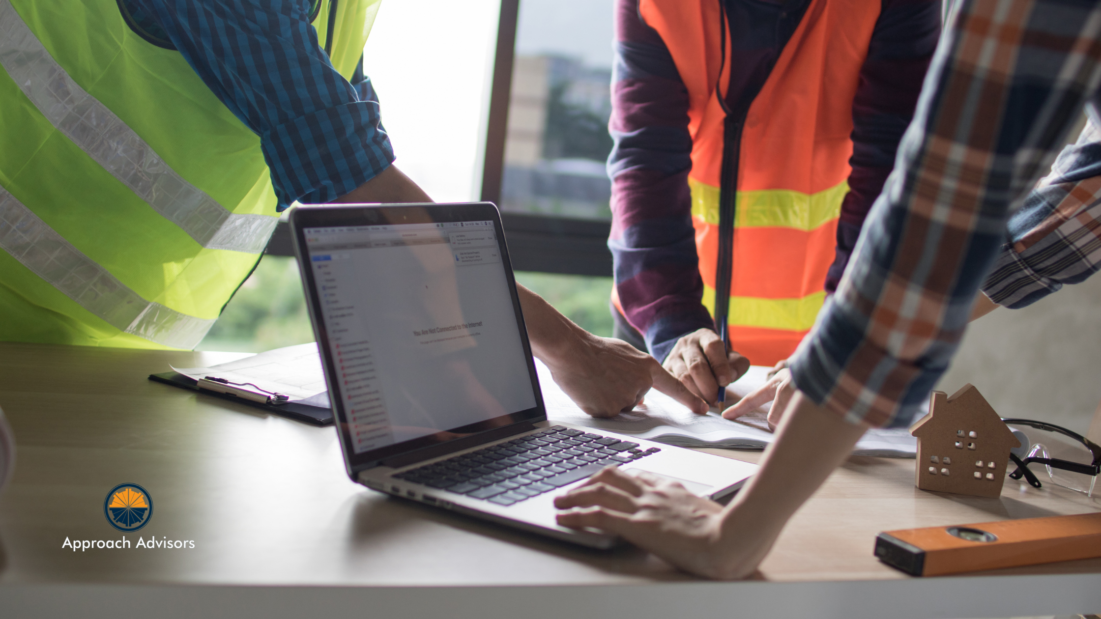 Construction team reviewing documents and laptop data during a Financial Planning session for a building project.